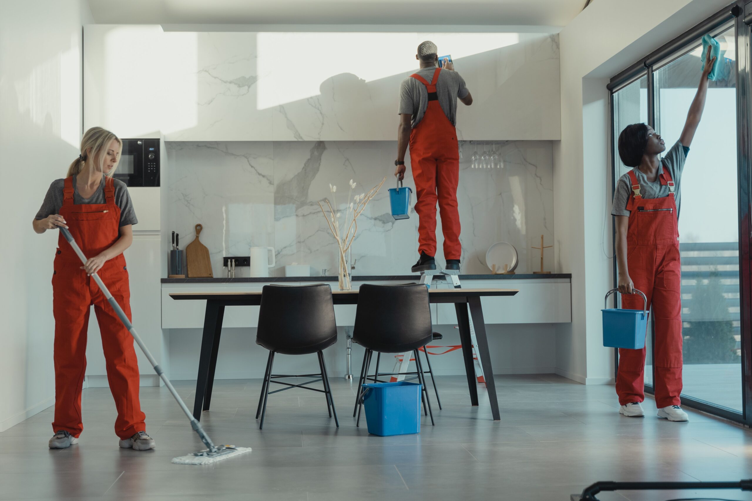 About Group of cleaners in red uniforms mopping and wiping glass in a modern dining room.